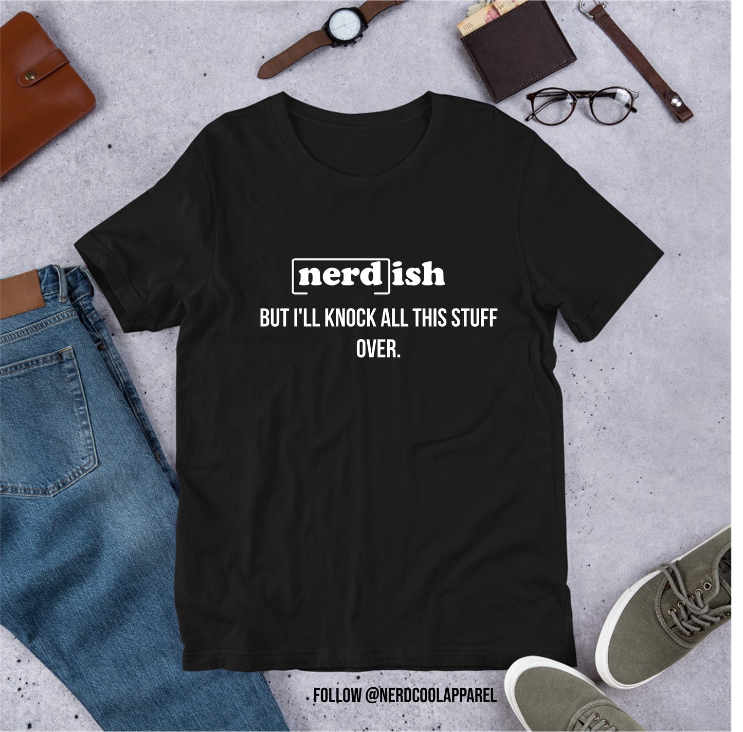 Black t-shirt with 'nerd-ish' text on a gray surface with jeans, shoes, and accessories.