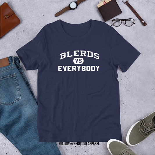 Navy blue t-shirt with 'BLERDS VS EVERYBODY' text on a gray surface with jeans, shoes, and accessories.