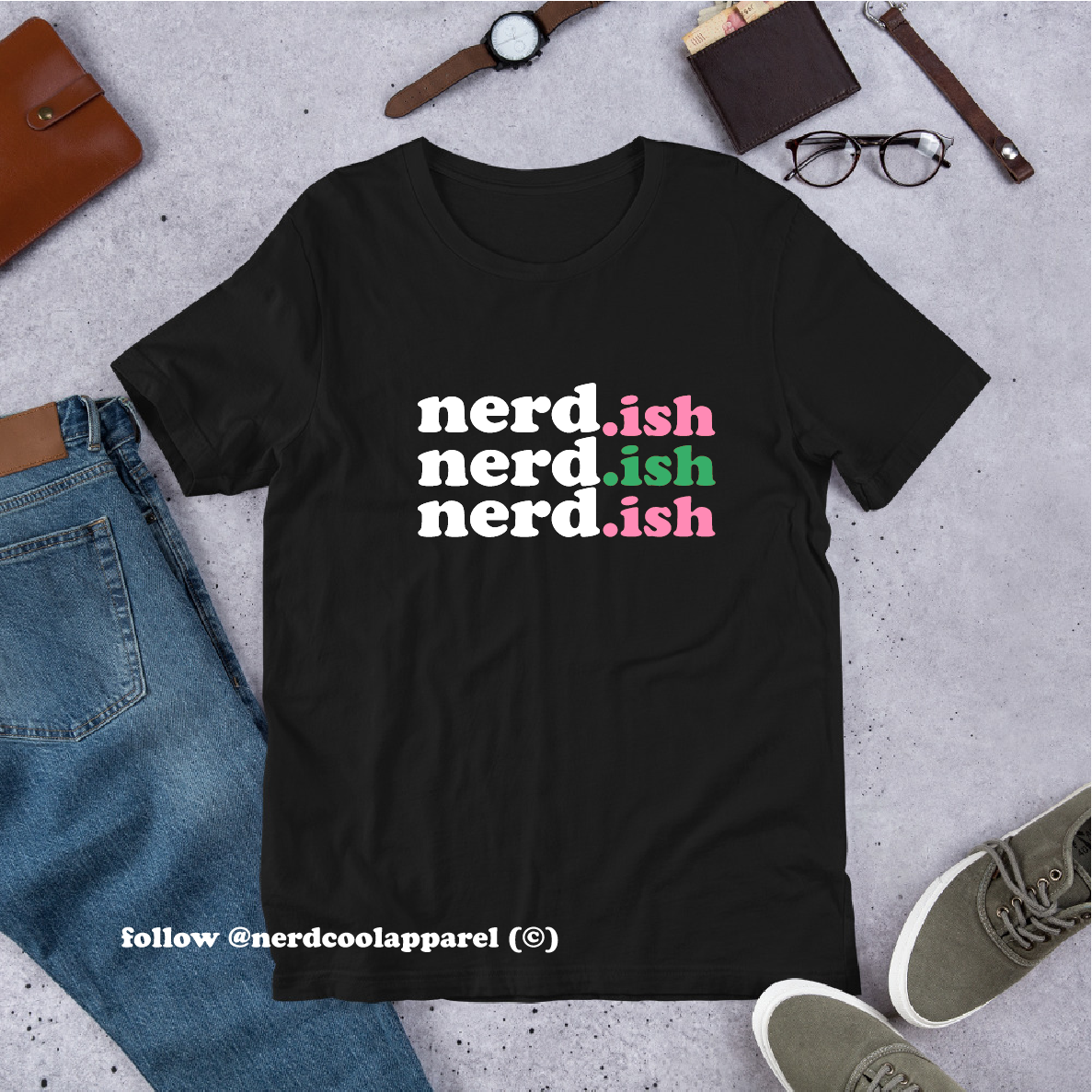 Black t-shirt with 'nerd.ish' text in different colors on a concrete surface with casual items.