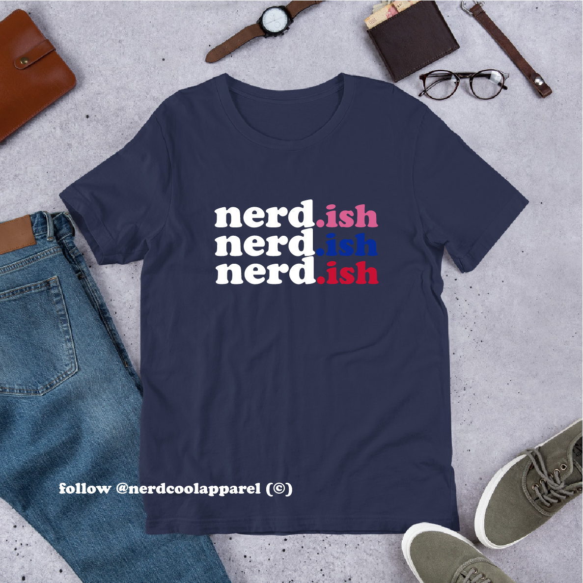 Navy blue t-shirt with 'nerd.ish' text on a gray surface with casual items around