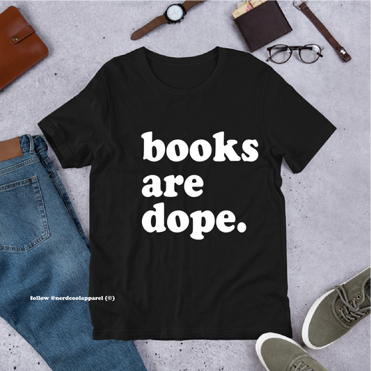Black t-shirt with 'books are dope.' text on a gray surface with jeans, shoes, and accessories.