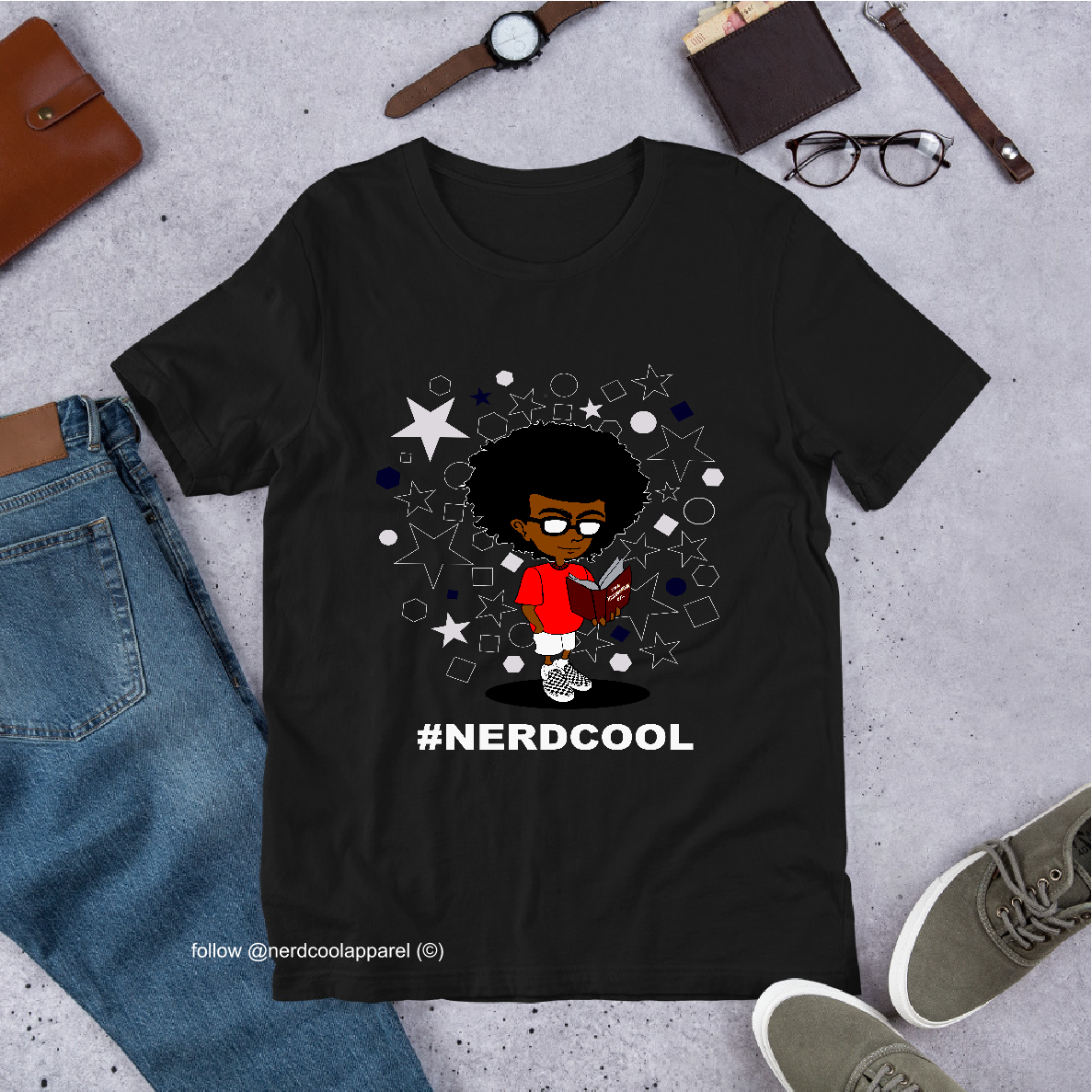Black t-shirt with a graphic design and '#NERDCOOL' text, surrounded by casual items on a concrete surface.