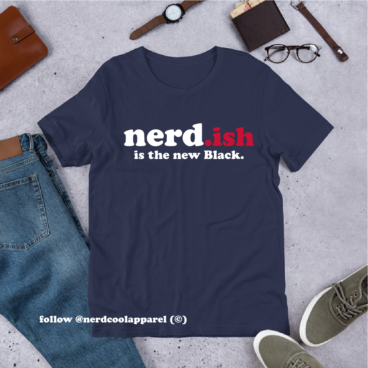 Navy blue t-shirt with 'nerd.ish is the new Black' text on a gray surface with jeans, shoes, and accessories.