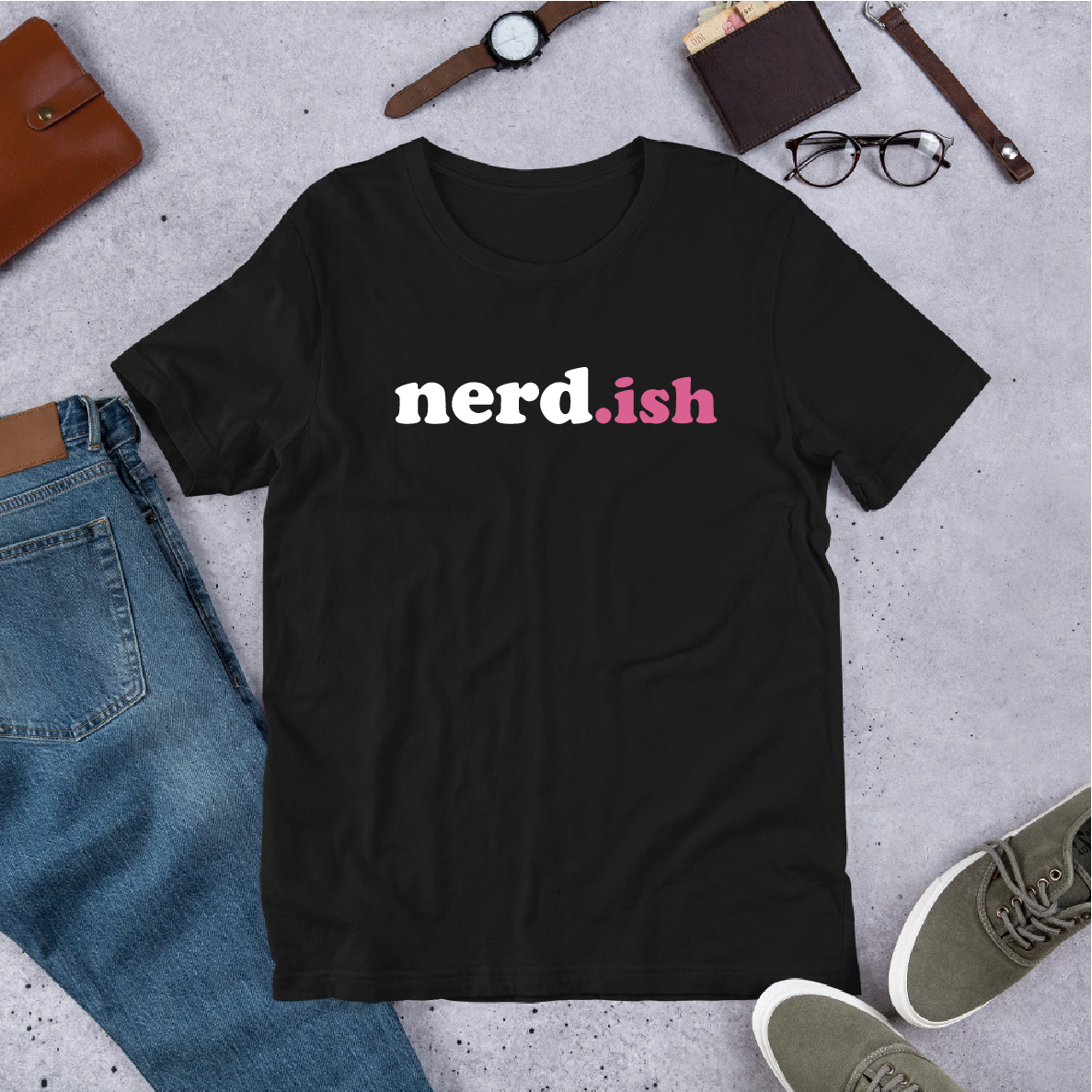 Black t-shirt with 'nerd.ish' text on a concrete surface with casual items around