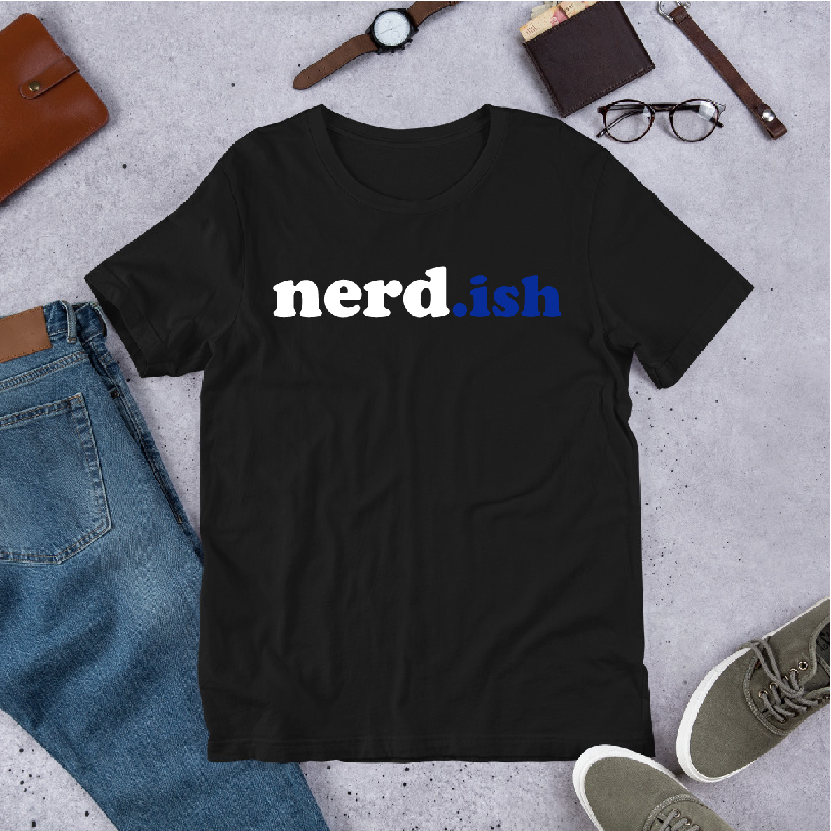 Black t-shirt with 'nerd.ish' text on a gray surface with jeans, shoes, and accessories.
