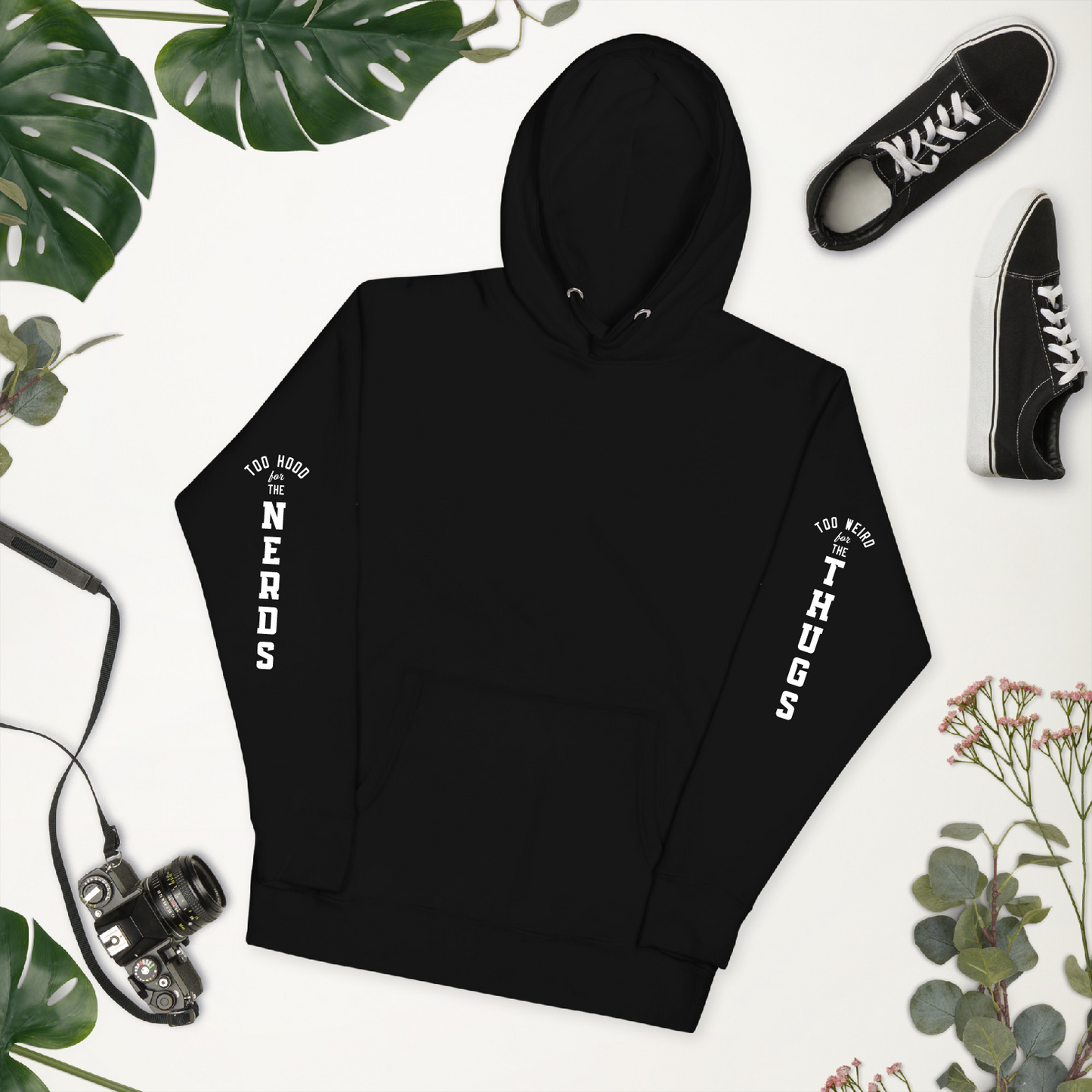 Black hoodie with white text on a white background with plants and shoes. Front