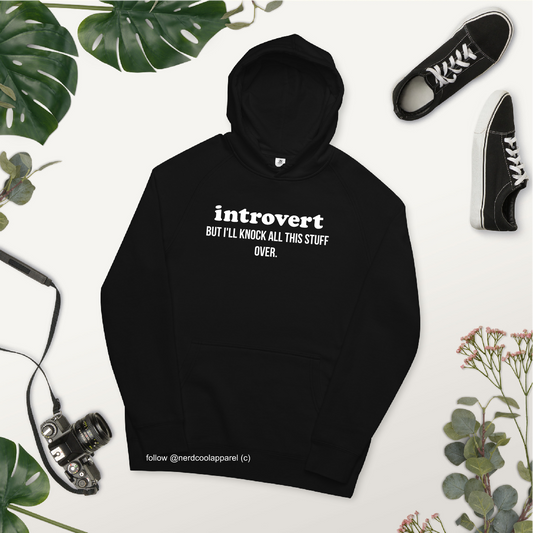 Black hoodie with 'introvert but I'll knock all this stuff over' text, surrounded by plants and shoes on a white background.