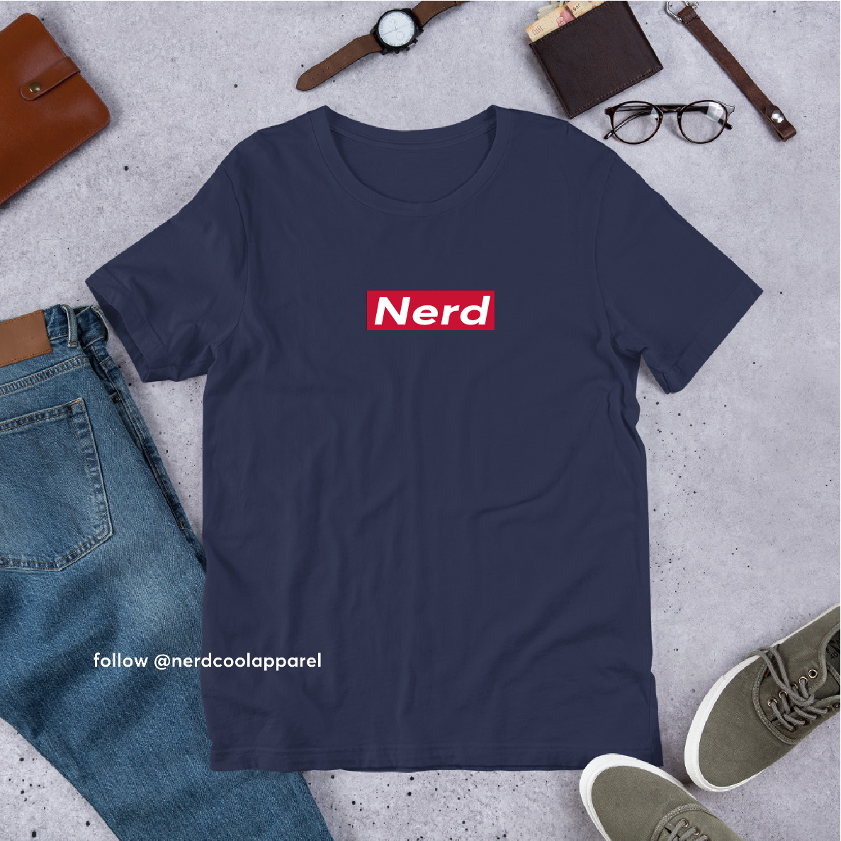 Navy blue t-shirt with 'Nerd' logo on a gray surface with jeans, shoes, and accessories.