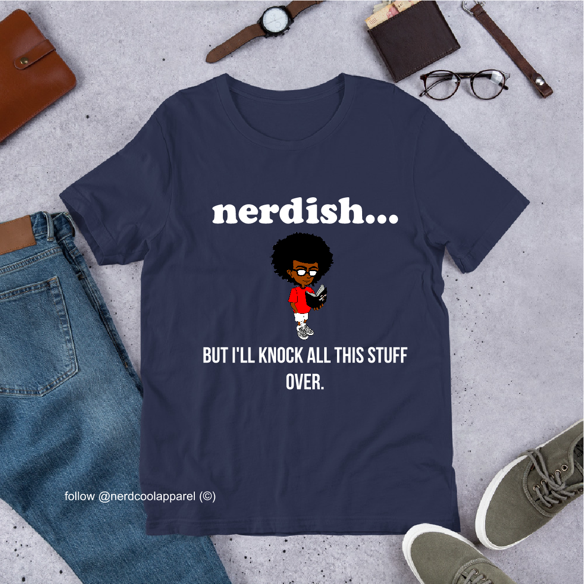 Navy blue t-shirt with 'nerdish...' graphic and text on a concrete surface with jeans, shoes, and accessories.