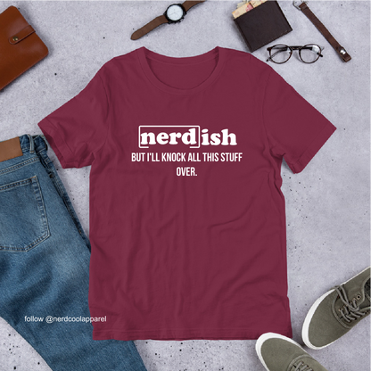 Maroon t-shirt with 'nerdish' text on a gray surface with jeans, shoes, and accessories.