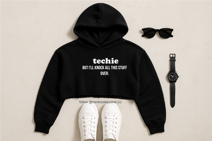Black hoodie with text, white sneakers, sunglasses, and watch on a beige background