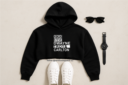 Black hoodie with text, white sneakers, sunglasses, and watch on a beige background
